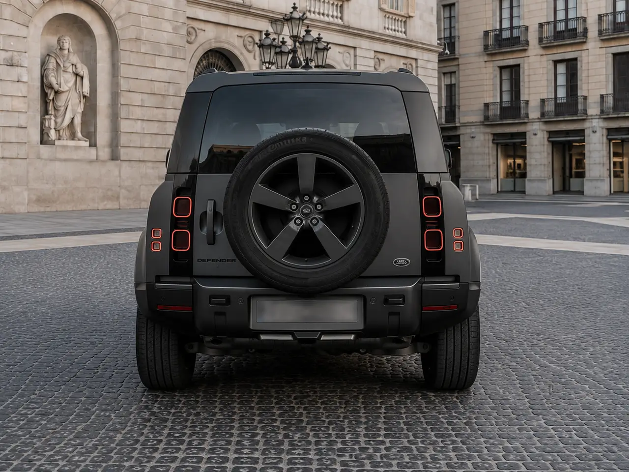 Land Rover Defender 2024, rear view — Lisbon Luxury Car Rental, Lisbon. The 2024 Land Rover Defender brings 400 hp and seven seats to a fleet mostly built around…